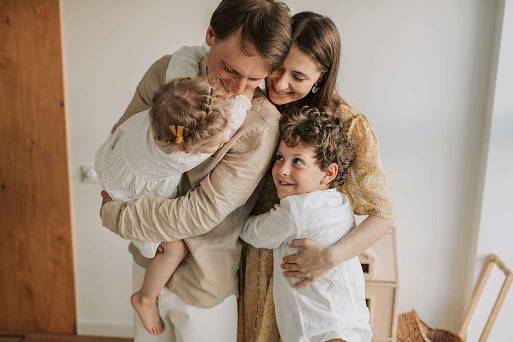 En familie på fire, to barn og to voksne som klemmer hverandre.
