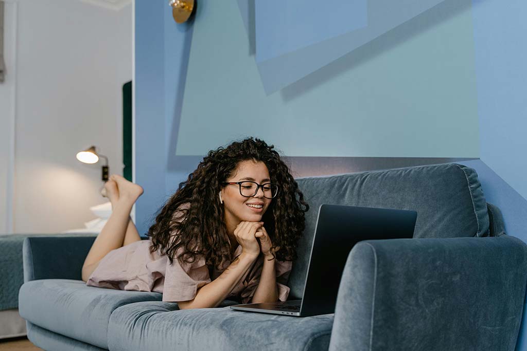 En dame som slapper av i ryddige omgivelser på en sofa med et smil.