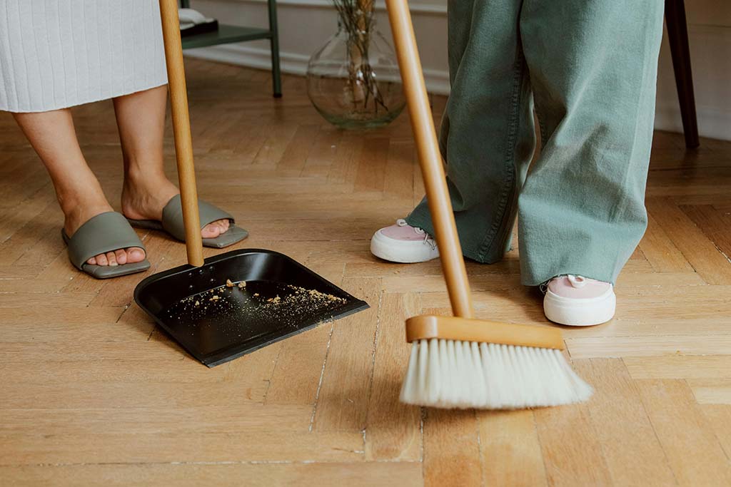 To personer med kost og feiebrett under flyttevasken i bod, kjeller og loftet.