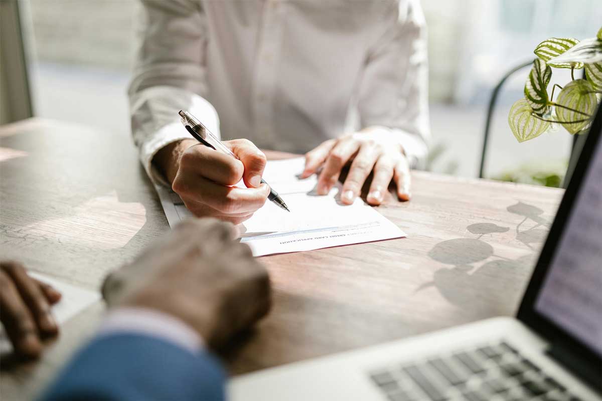 Pårørende som signerer et dokument angående et dødsfall, mens en advokat sitter foran personen.