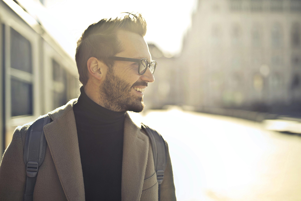 Mann som smiler og er ute i solen i hverdagen